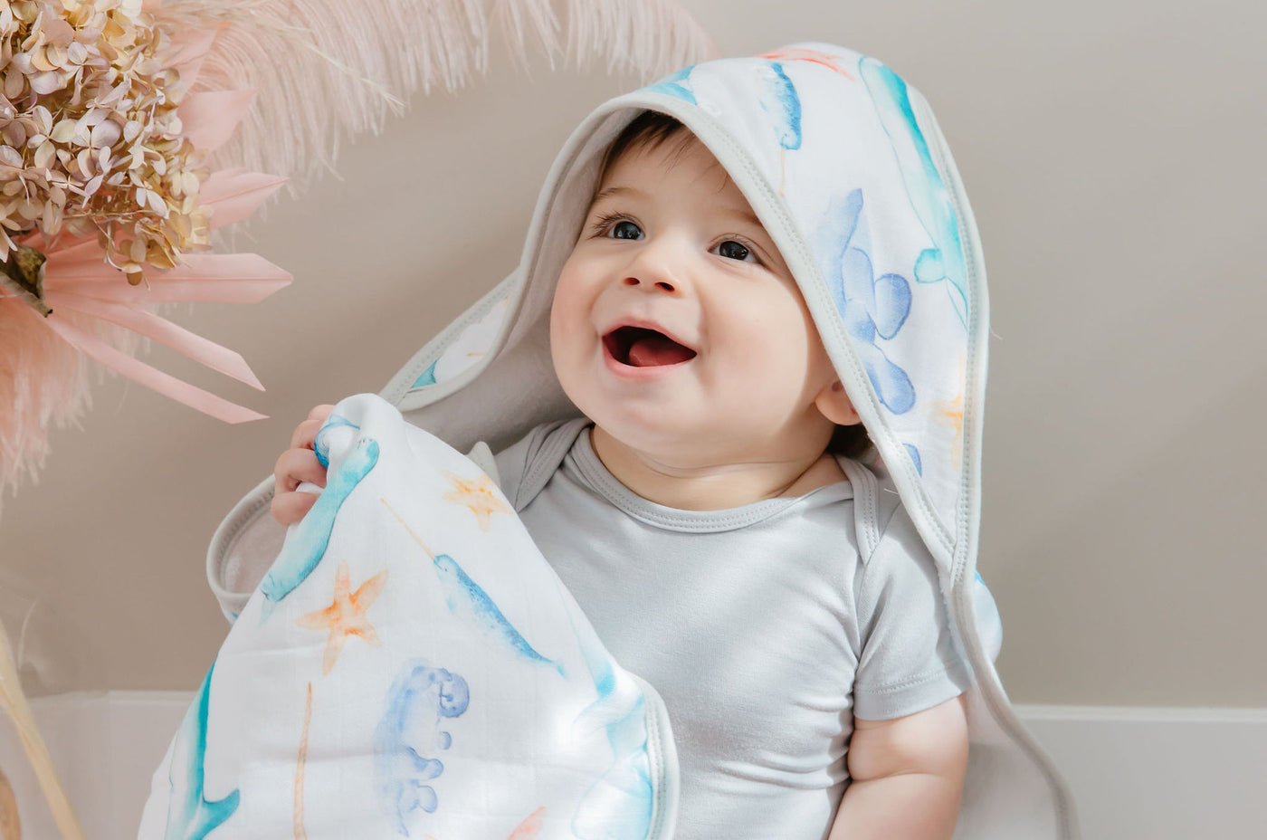 Happy baby boy in bamboo hooded towel in West Coast Babes pattern